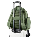 Sage Skip Hop Diaper Bag Backpack mounted on a wheeled luggage handle, featuring padded straps and side pocket.