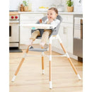 A baby sitting in the Skip Hop EON 4-in-1 High Chair in grey and white, enjoying a meal in a modern kitchen.