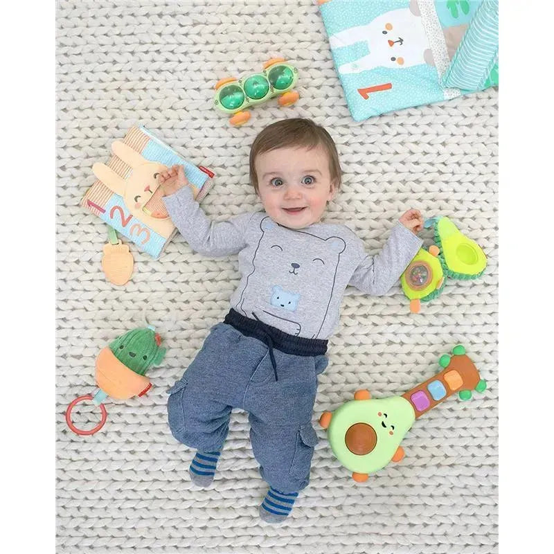 Baby lying on a textured blanket surrounded by toys, including the Skip Hop Cactus Jitter Hanging Toy, with a joyful expression.