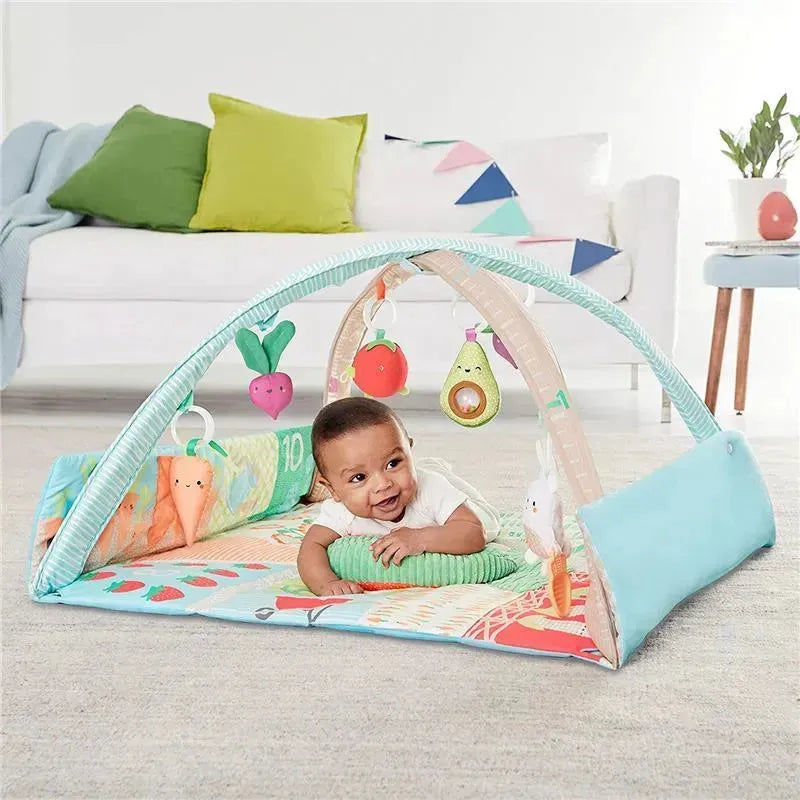 Skip Hop Farmstand Activity Gym features a smiling baby lying on a colorful play mat with hanging fruit toys.