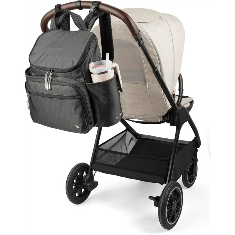 Skip Hop Forma Next Backpack in black attached to a stroller, features multiple compartments and a side pocket for a drink.