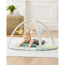 Baby playing on a Skip Hop Garden Oasis Activity Gym with hanging toys, surrounded by a soft mat.