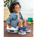 Child sitting on a Skip Hop Go Time 3-In-1 Potty, smiling, wearing a denim jacket and colorful shoes.