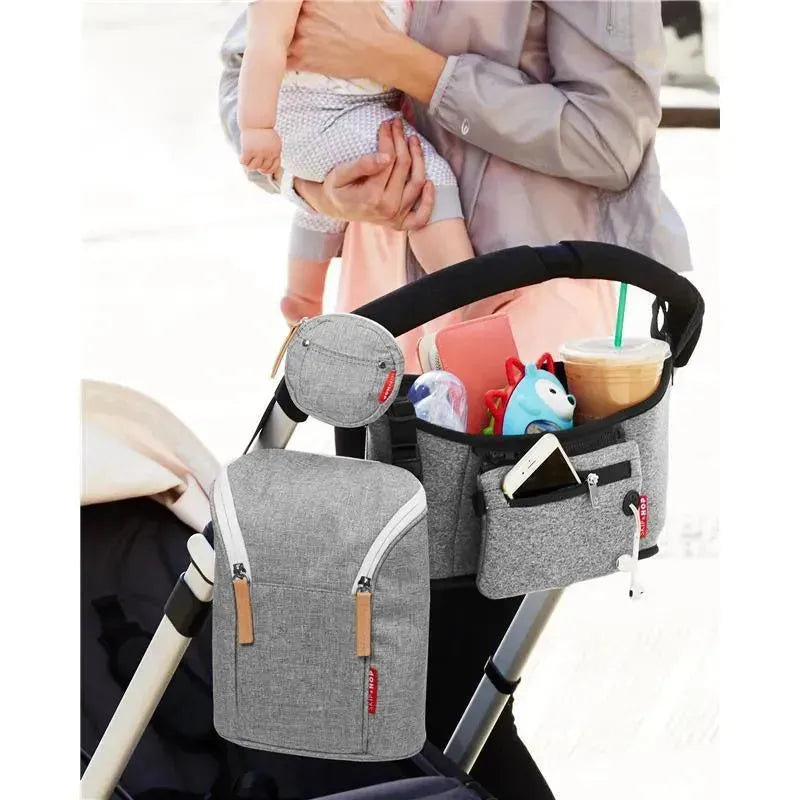 Grey melange Grab & Go Double Bottle Bag attached to a stroller, holding baby items, toys, and a drink.