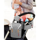Grey melange Grab & Go Double Bottle Bag attached to a stroller, holding baby items, toys, and a drink.