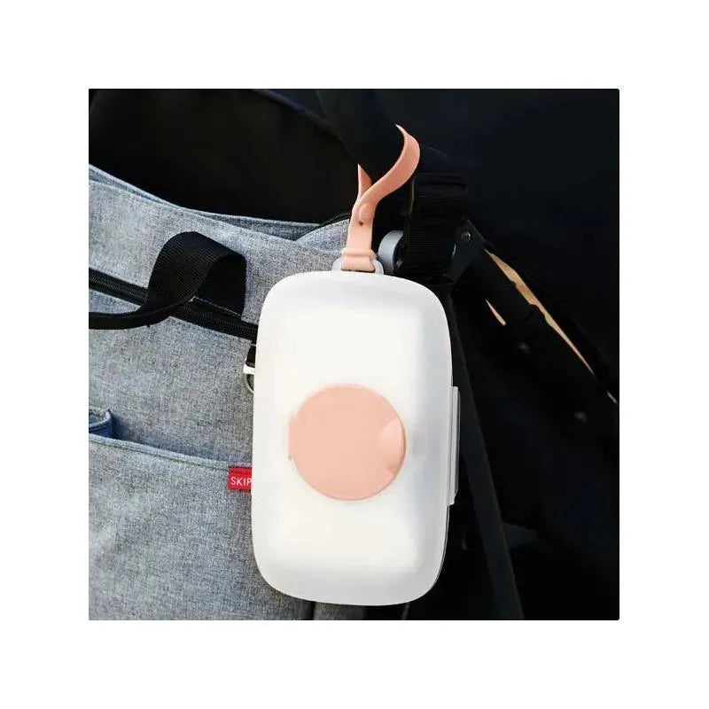 Blush Skip Hop Grab & Go Snug Seal Wipes Case attached to a bag, featuring a soft pink latch and round button.