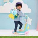 A young child on a blue unicorn-themed ride-on toy, wearing a helmet and a matching unicorn backpack, smiling against a colorful background.