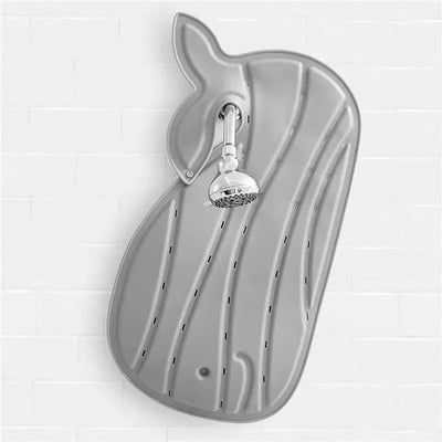 Non-slip grey Moby bath mat shaped like a whale, featuring water drainage holes and a showerhead attached above.