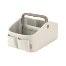 Light beige Skip Hop diaper caddy with a brown handle, featuring multiple compartments for organizing baby essentials.