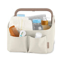 Light beige diaper caddy with a handle, filled with diapers, bottles, a comb, and a thermometer, designed for nursery organization.