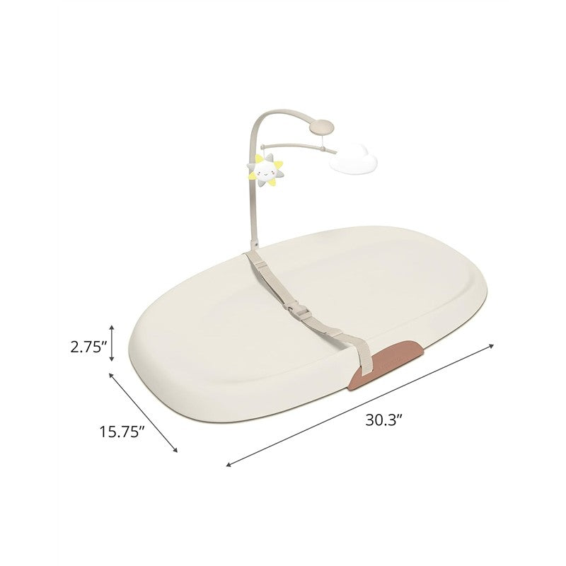 Skip Hop Nursery Style Wipe-Clean Changing Pad in oat color, featuring a safety strap and a detachable toy bar with sun and cloud.
