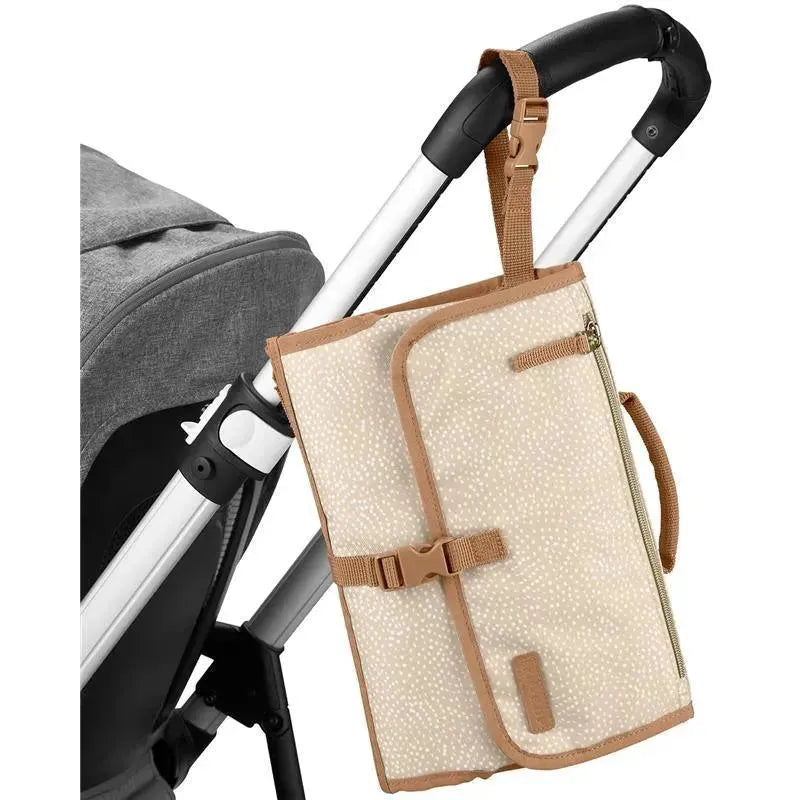 Portable baby changing pad in beige swirl dot pattern, attached to a stroller handle with a strap, featuring a zippered pocket.