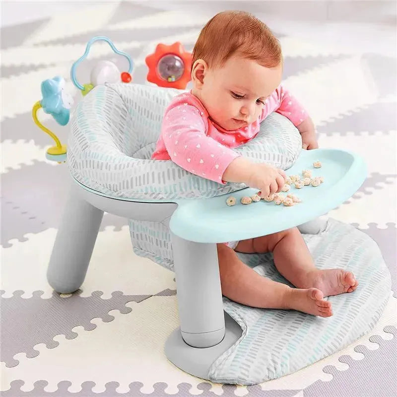 Baby sitting in a Skip Hop Silver Lining Cloud 2-in-1 Activity Floor Seat, playing with snacks on a light blue tray.