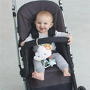 Baby smiling in a stroller, holding onto a Skip Hop Silver Lining Cloud Jitter Toy with colorful features and dangling characters.