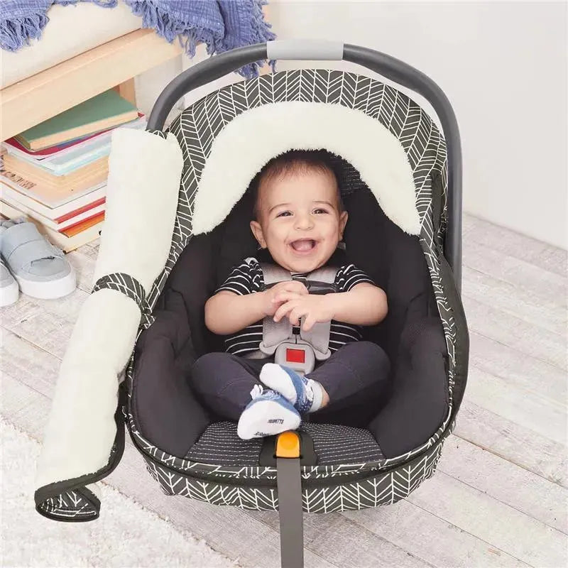 Grey feather-patterned car seat cover with a smiling baby inside, secured in a car seat with a soft lining.
