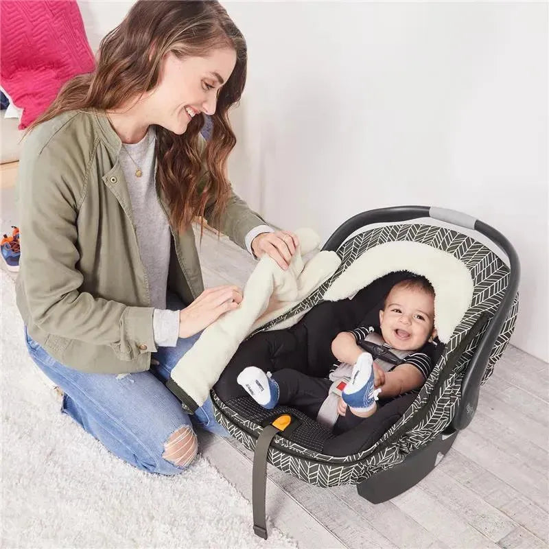 Mother adjusts a soft, cream-colored blanket over a smiling baby in a Skip Hop car seat cover featuring a grey feather design.