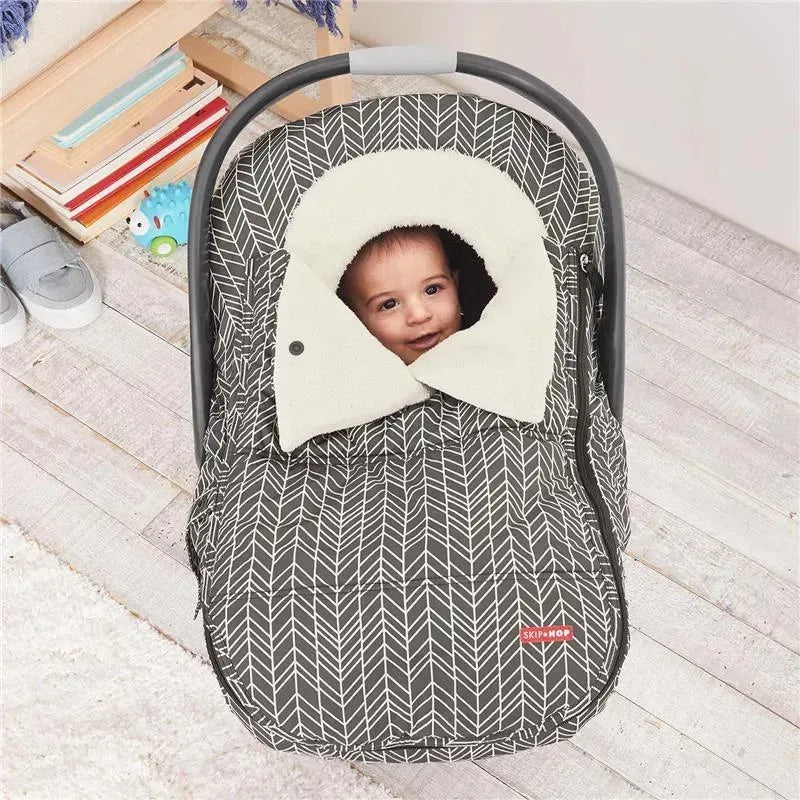 Car seat cover in grey feather pattern with a cozy white hood, featuring a smiling baby inside.