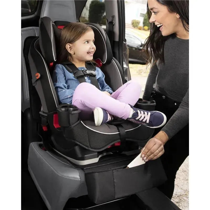 Child in a car seat smiles at a woman, showcasing the Skip Hop Clean Child Car Seat Protector with storage pocket.