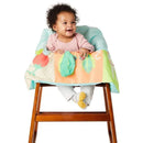 Baby seated in a high chair with a colorful Skip Hop Farmstand Shopping Cart Cover featuring vegetable designs and textures.