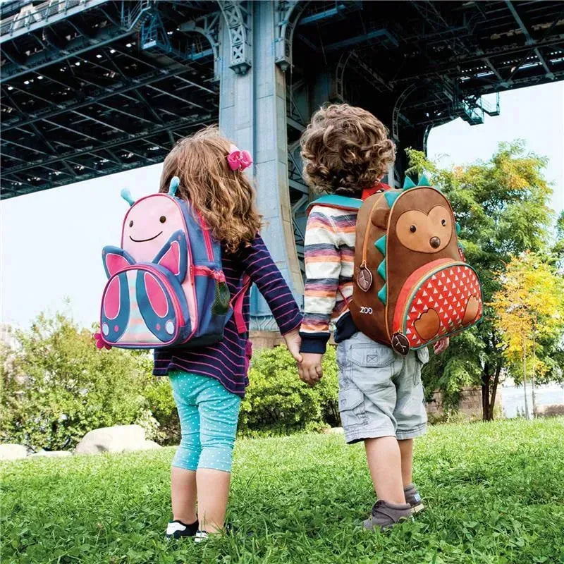 Children holding hands, wearing colorful backpacks: a butterfly design on one and a bear on the other.