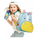 Child smiling while holding a blue water bottle and wearing a Skip Hop Zoo unicorn backpack with a yellow polka dot design.