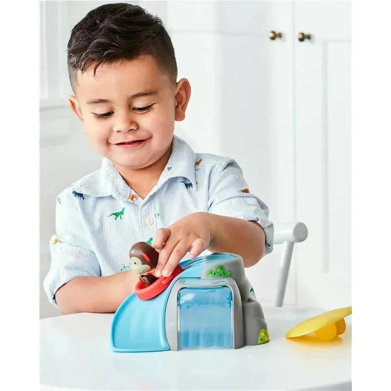 Young boy playing with the Skip Hop Zoo Outdoor Adventure Playset, featuring a monkey toy and a water slide.