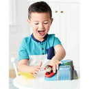 A boy joyfully plays with the Skip Hop Zoo Outdoor Adventure Playset, guiding a monkey figure down a slide.