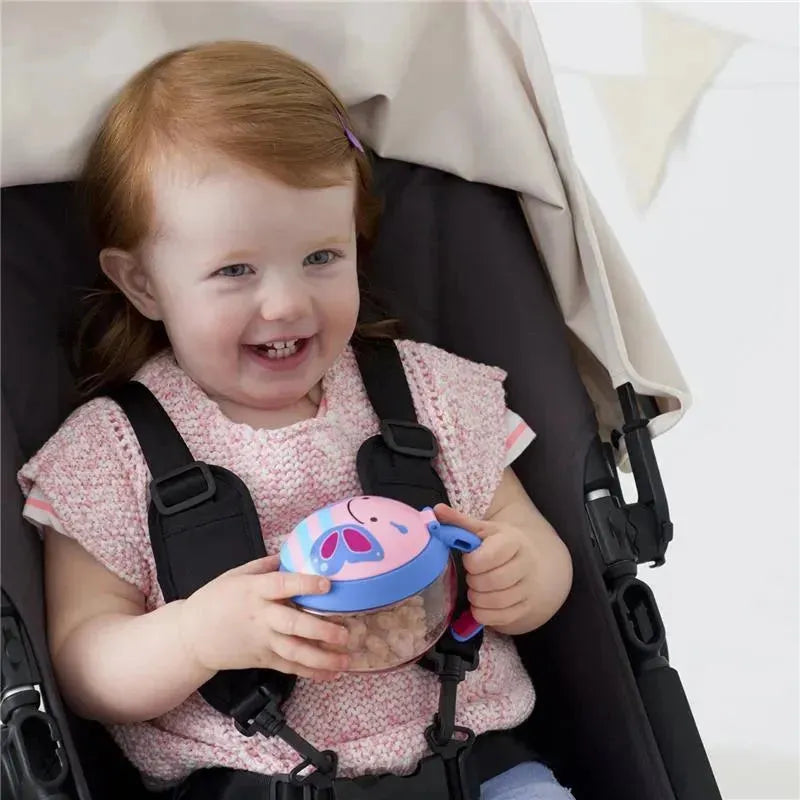 Toddler with red hair smiling while holding a butterfly-themed Skip Hop Zoo Snack Cup in a stroller.