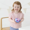 Smiling toddler holding a Skip Hop Zoo Snack Cup in the shape of a butterfly, wearing a pink sweater.