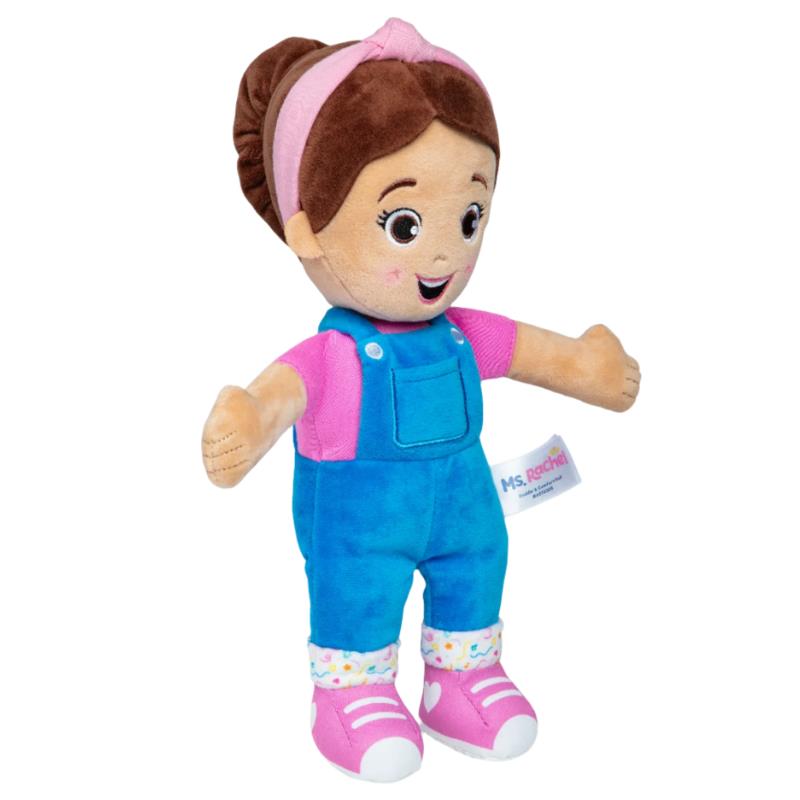 Cuddly Ms. Rachel doll wearing blue overalls and a pink top with a smiling face and brown hair in a bun.