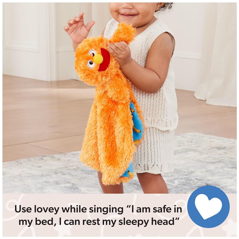 A smiling toddler holds a bright orange security blanket with a character face, on a soft rug with a message about bedtime singing.