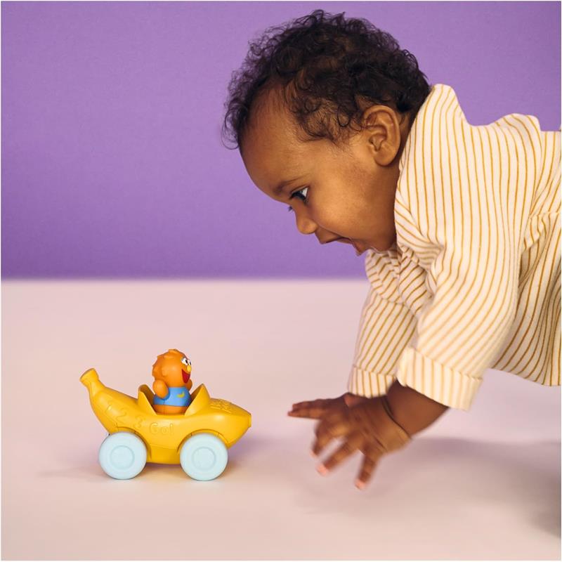 Baby reaching for a yellow toy vehicle with a pull-along design and a click-in figure smiling from the seat.