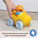 Yellow banana car toy with a smiling figure, being held by a child’s hand, ready to race forward when pulled back.
