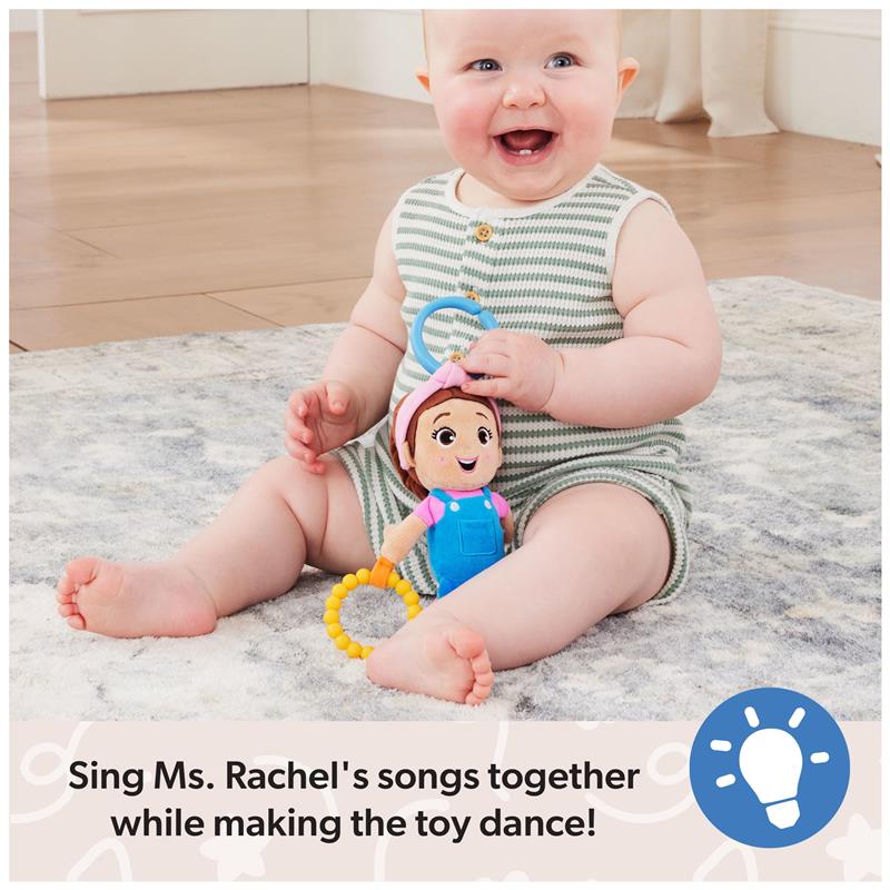 Baby sitting on a soft carpet, happily holding the Spin Master Ms. Rachel Sensory Take-Along Toy with colorful rings.