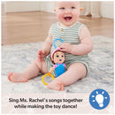 Baby sitting on a soft carpet, happily holding the Spin Master Ms. Rachel Sensory Take-Along Toy with colorful rings.
