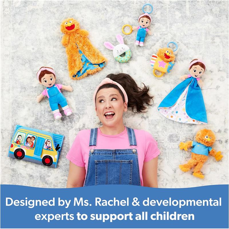 Ms. Rachel smiles surrounded by colorful toys, including her Speak N Sing Doll, promoting developmental support for children.