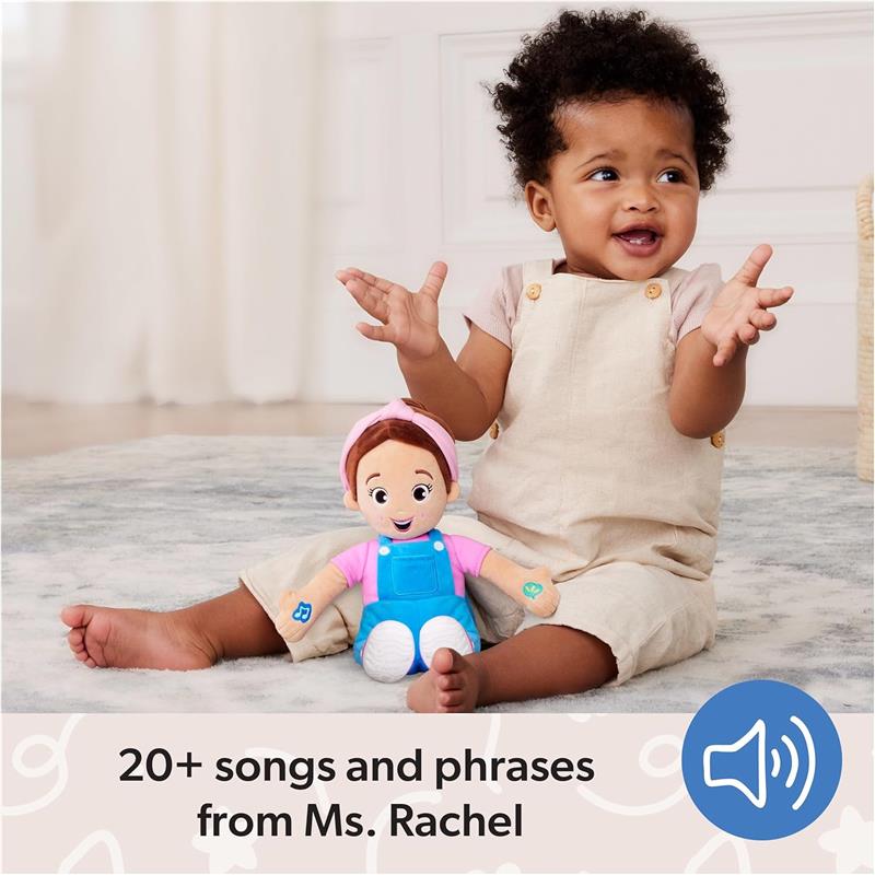 Child in beige overalls joyfully plays with Spin Master Ms. Rachel Speak N Sing Doll, which features a smiling character and sounds.