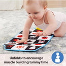 Baby crawling on a colorful patterned play mat designed to promote tummy time and muscle development.