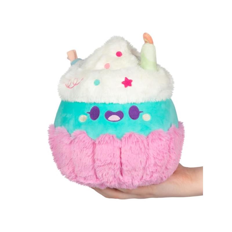 Mini plush cupcake with a smiling face, featuring pastel colors and decorative toppings, held in a hand.