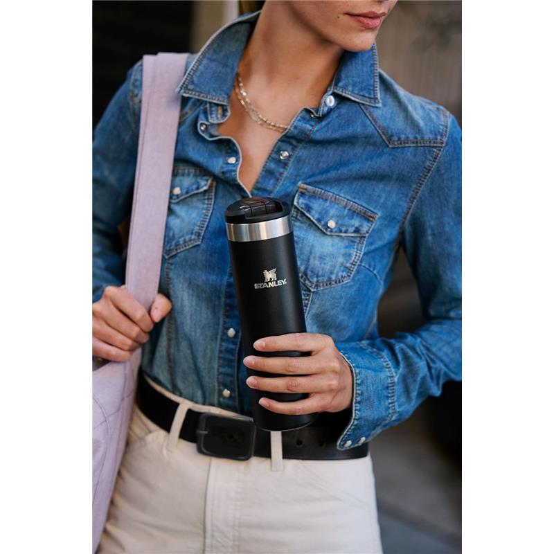 Stanley The Transit Fliptop Mug 20 oz in Rose Quartz held by a person in a denim shirt, with a black belt and a light bag.
