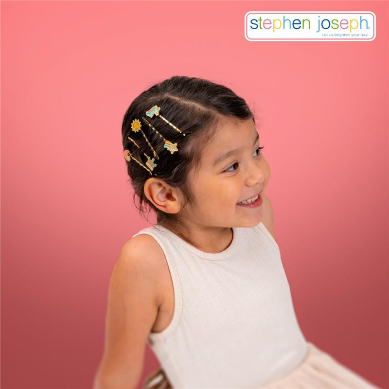 A smiling young girl wearing a white sleeveless top, showcasing colorful bunny hair pins in her hair against a pink background.
