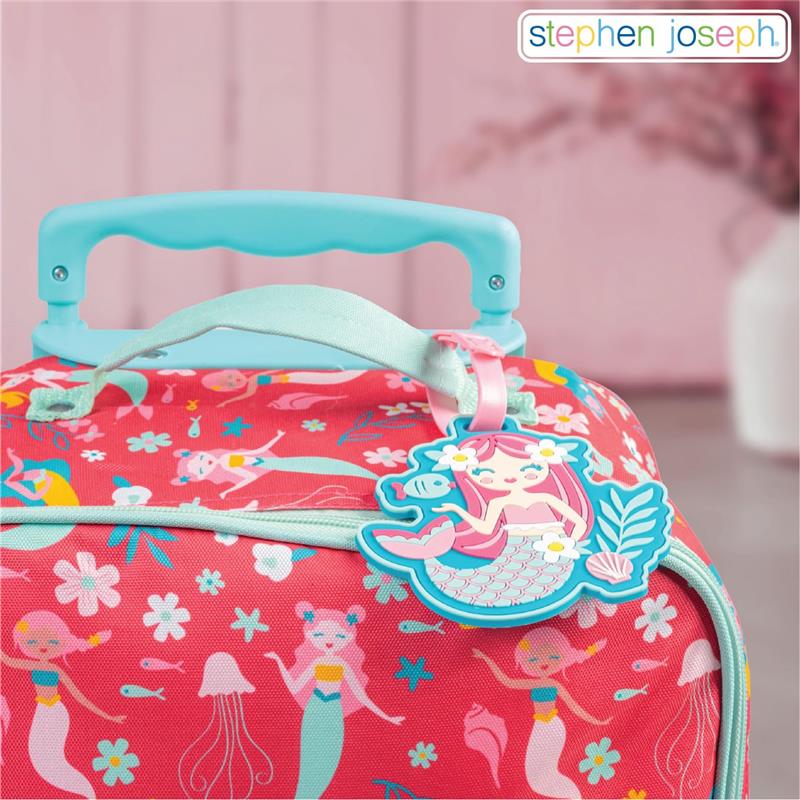 Luggage tag shaped like a mermaid attached to a bright pink suitcase decorated with mermaid and floral patterns.