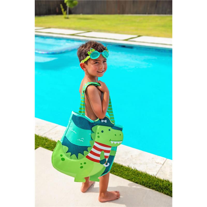 Child wearing Stephen Joseph Fire swim goggles, smiling by a pool, holding a green dinosaur-themed bag.