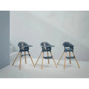 Stokke Clikk High Chair in Fjord Blue, featuring a modern design with wooden legs and safety harness, set against a neutral background.