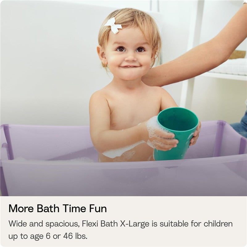 Child with a green cup in a Stokke Flexi Bath Tub X-Large, Ocean Blue, enjoying bath time with bubbles.