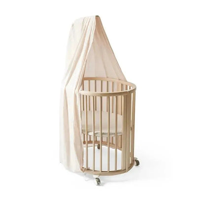 Stokke Sleepi Canopy by Pehr in blush color, featuring a wooden crib with rounded edges and a soft fabric canopy.