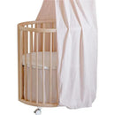 Stokke Sleepi Mini Bed Skirt by Pehr in blush, featured on a circular crib with a striped mattress.