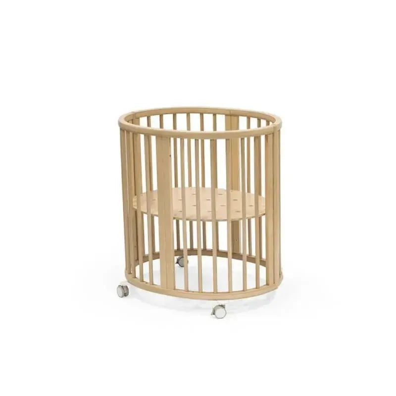 Natural wooden Stokke Sleepi Mini Bundle V3 crib with slatted design and wheels for mobility.