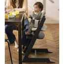 Stokke Tripp Trapp High Chair in Glacier Green, with a child seated, enjoying a snack at a dining table.
