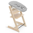 Stokke Tripp Trapp® Newborn chair in natural wood with a gray cushioned seat and safety harness.
